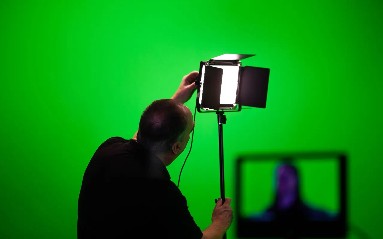 Technicien réglant un éclairage dans un studio sur fond vert